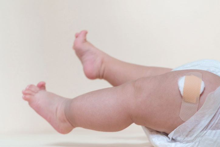 baby legs with bandage over injection site