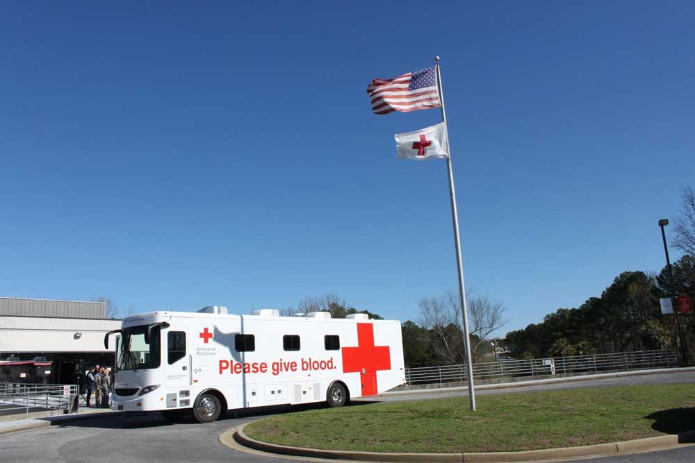 Red cross mobile parked in front of building 