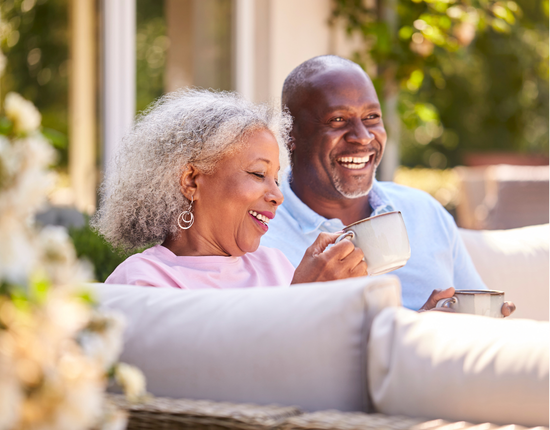 man and woman sitting on couch outside drinking coffee