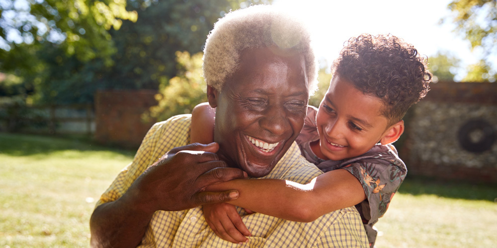 grandfather and grandchild smiling in the backyard