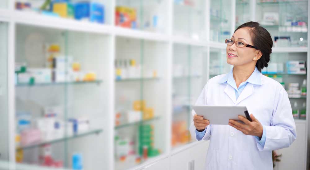 woman in white coat walking in pharmacy with bright medicine bottles