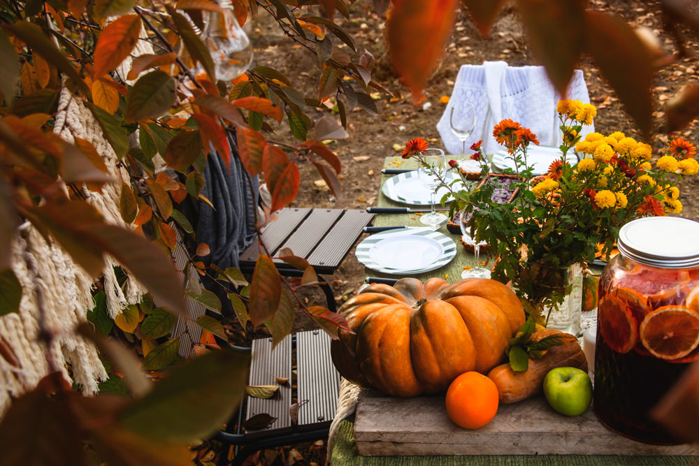 table set outside for holidays with pumpkins and fresh fruit
