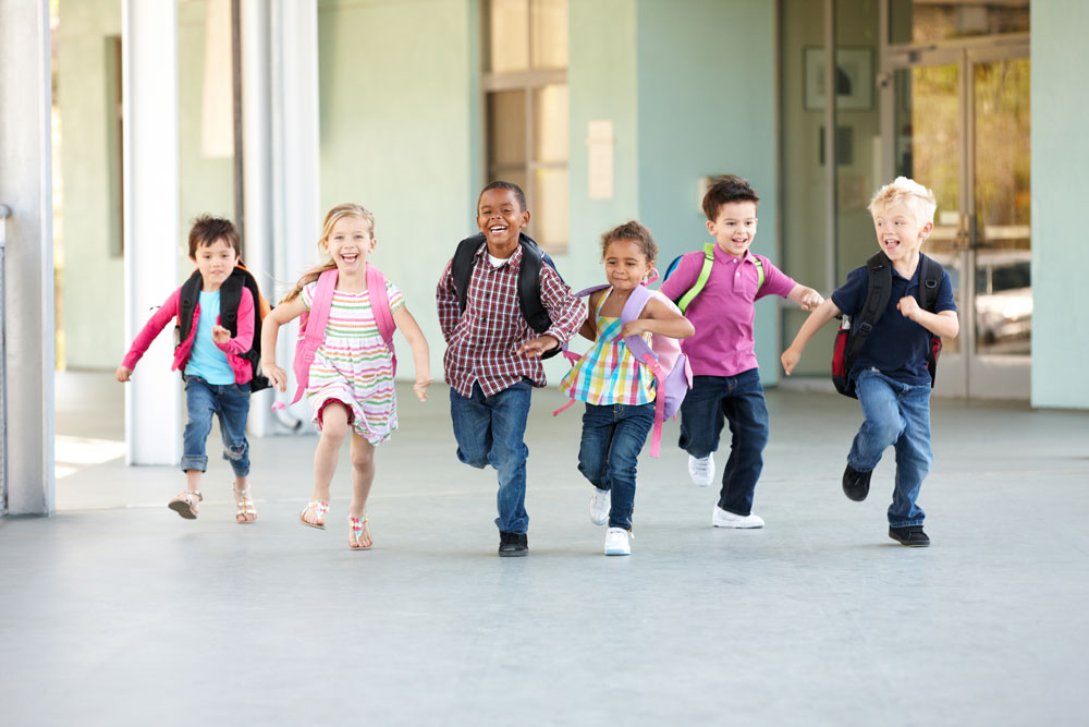 group of children with back packs running from school
