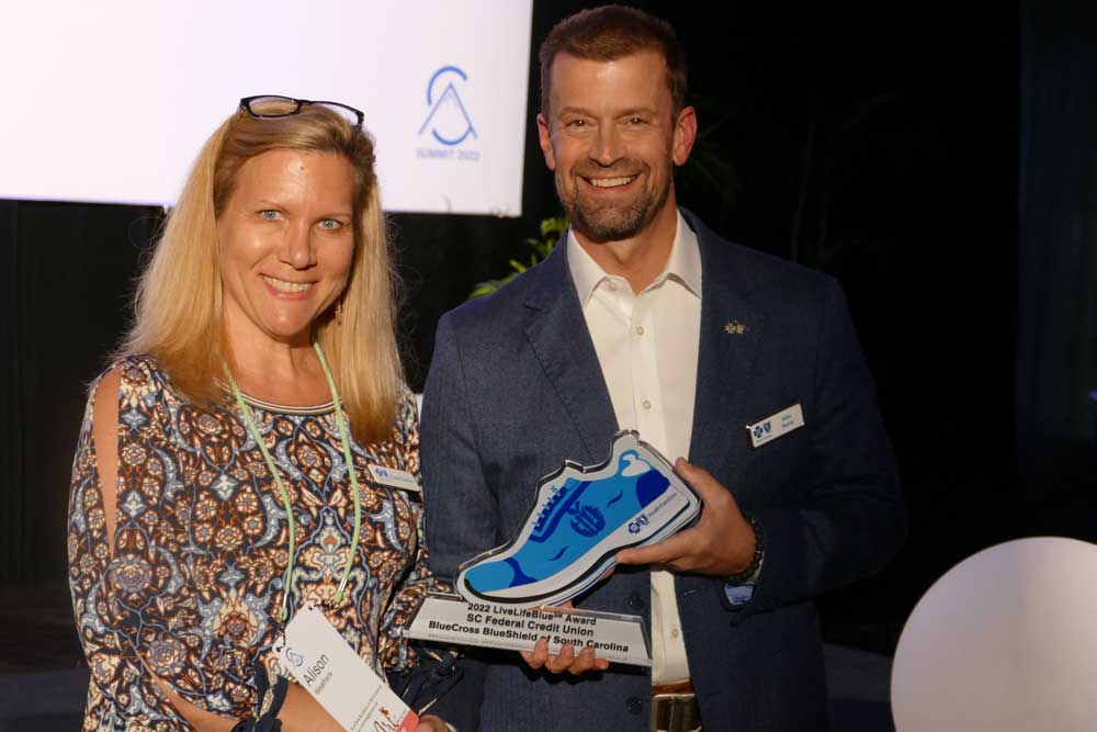 woman accepts blue shoe award from man in suit