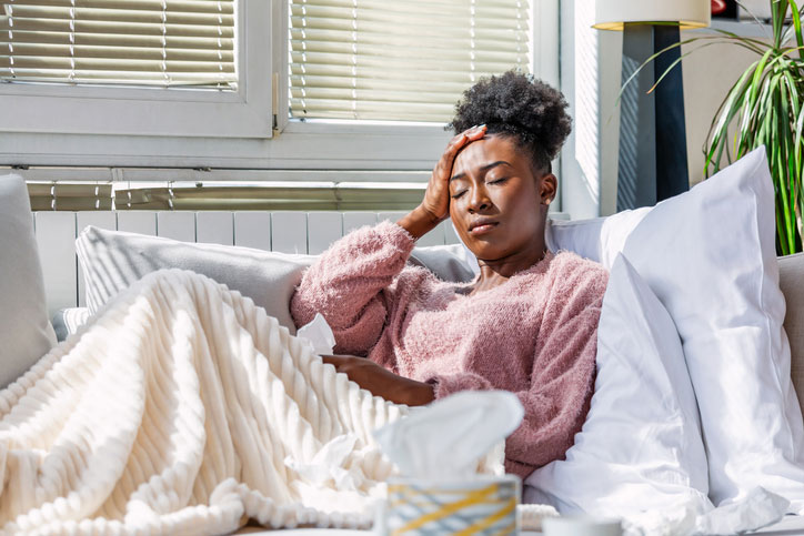 sick woman sitting on bed with tissues