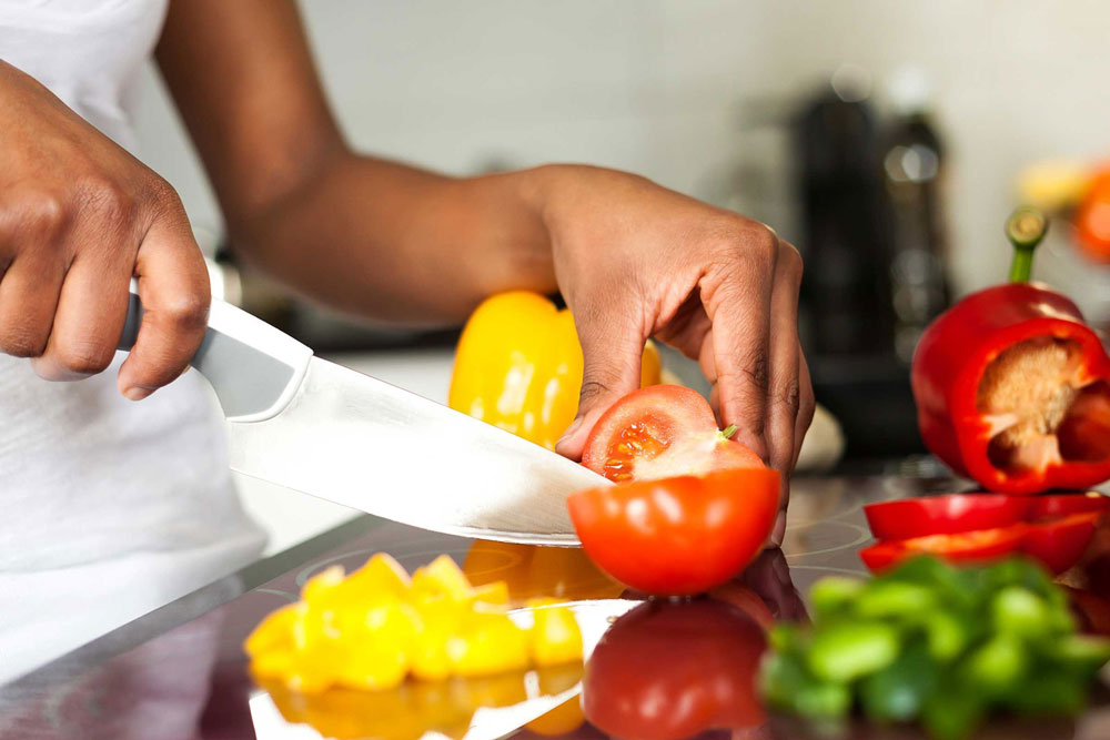 A person cuts vegetables on a kitchen counter.