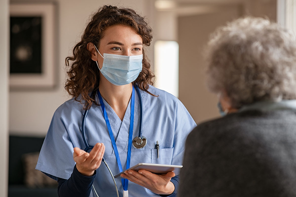 A female health care worker wears a face mask as she speaks with a patient