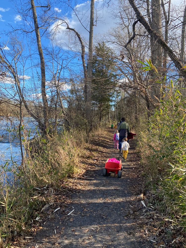 family walking trail by river in winter