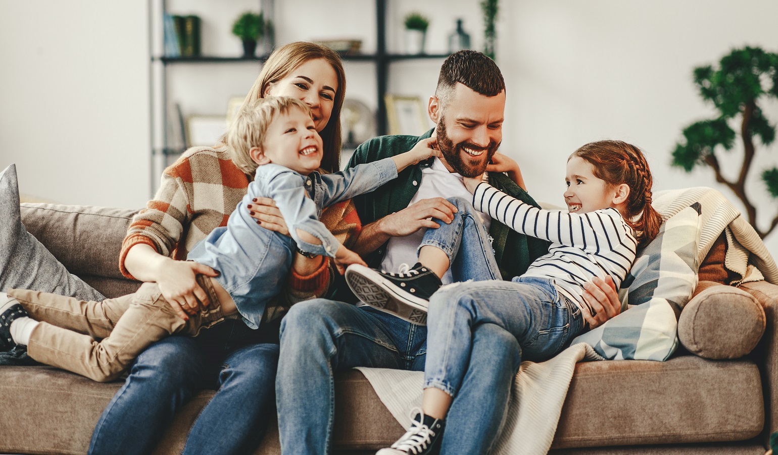 mother and father laughing with children on couch