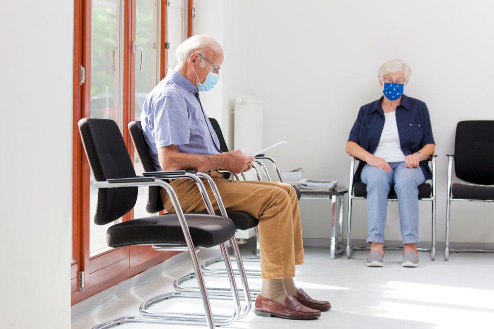 man and woman waiting at doctor's office in masks