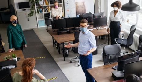 businessman addresses office of employees in masks