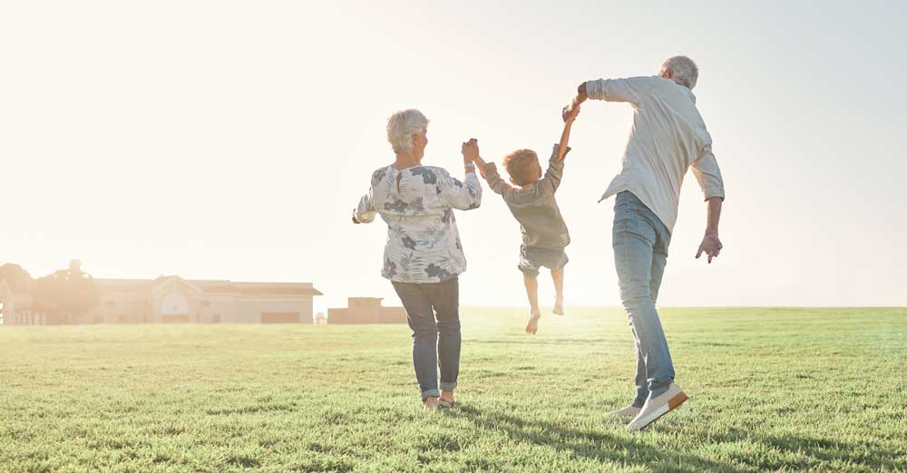 man and woman picking up little kid in field