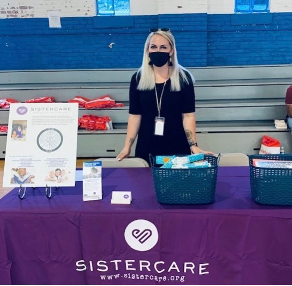 volunteer at a table with Sistercare materials 