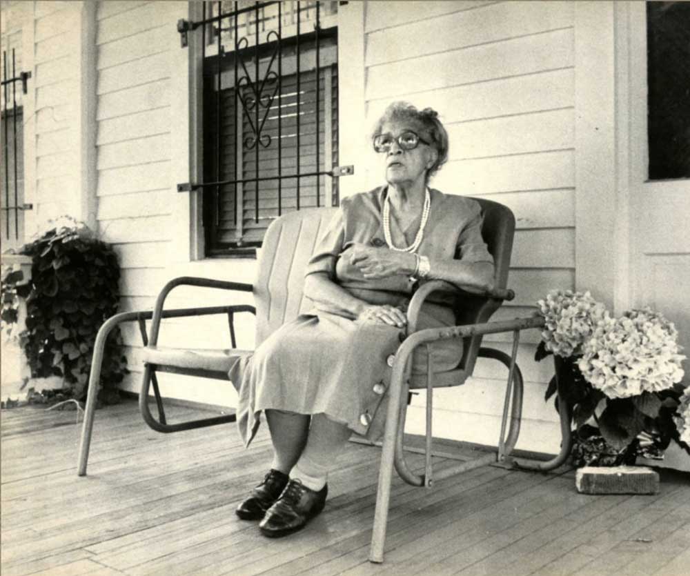 Historic image of modjeska sim-kind sitting in chair on porch outside