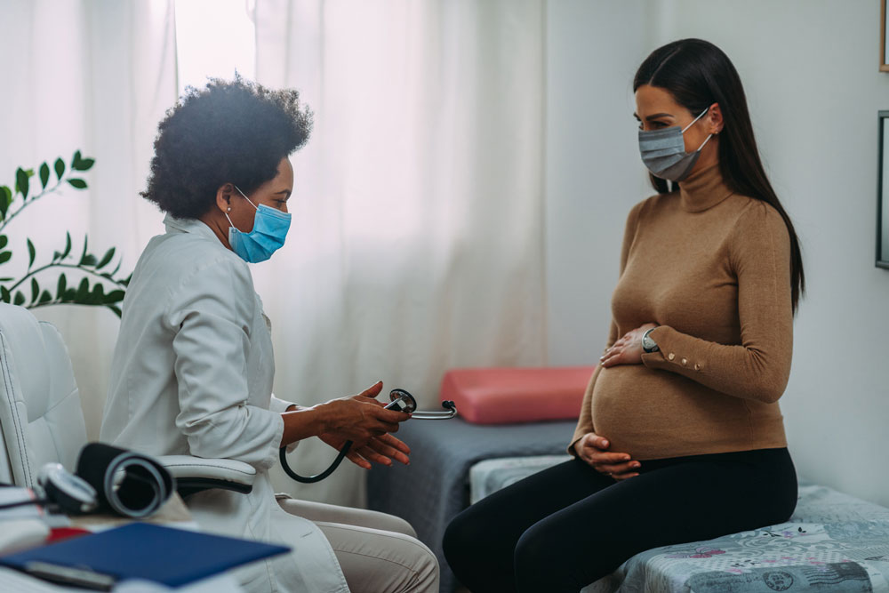 pregnant woman wearing mask in doctor office 