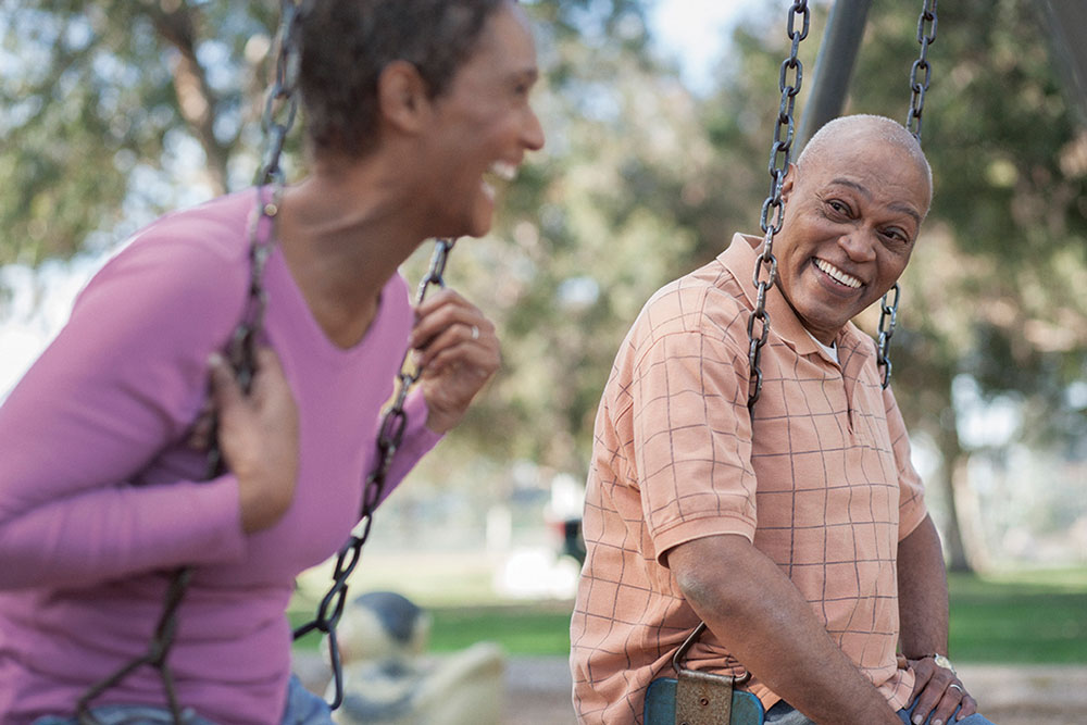 older man and woman smiling on swings