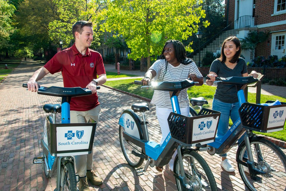 Man and two women walk with Blue Bikes in Columbia