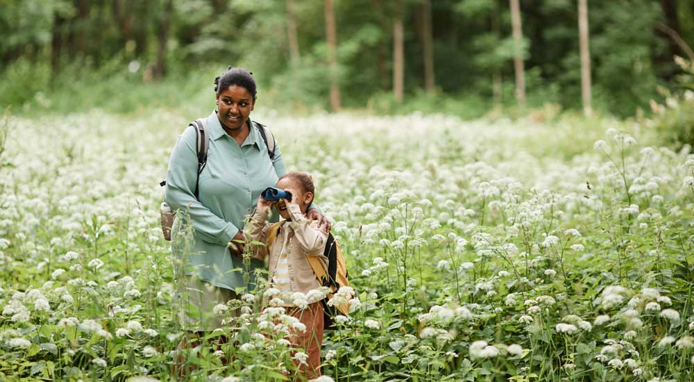 woman with girl in meadow with binoculars