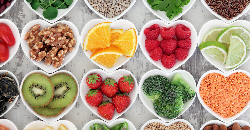A colorful assortment of fruits and vegetables beautifully arranged in heart-shaped bowls, showcasing vibrant natural hues.