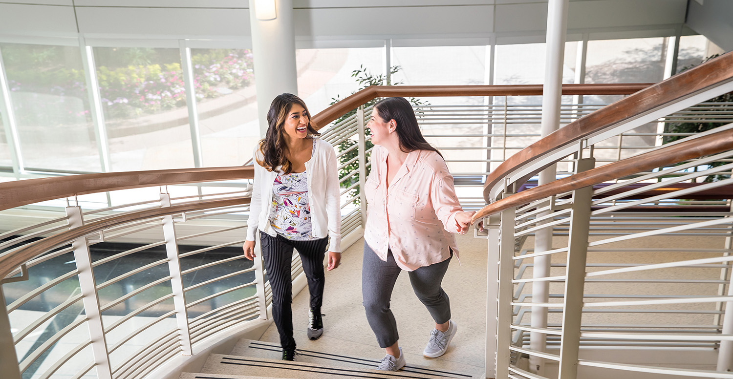 Two female coworkers walking up office steps