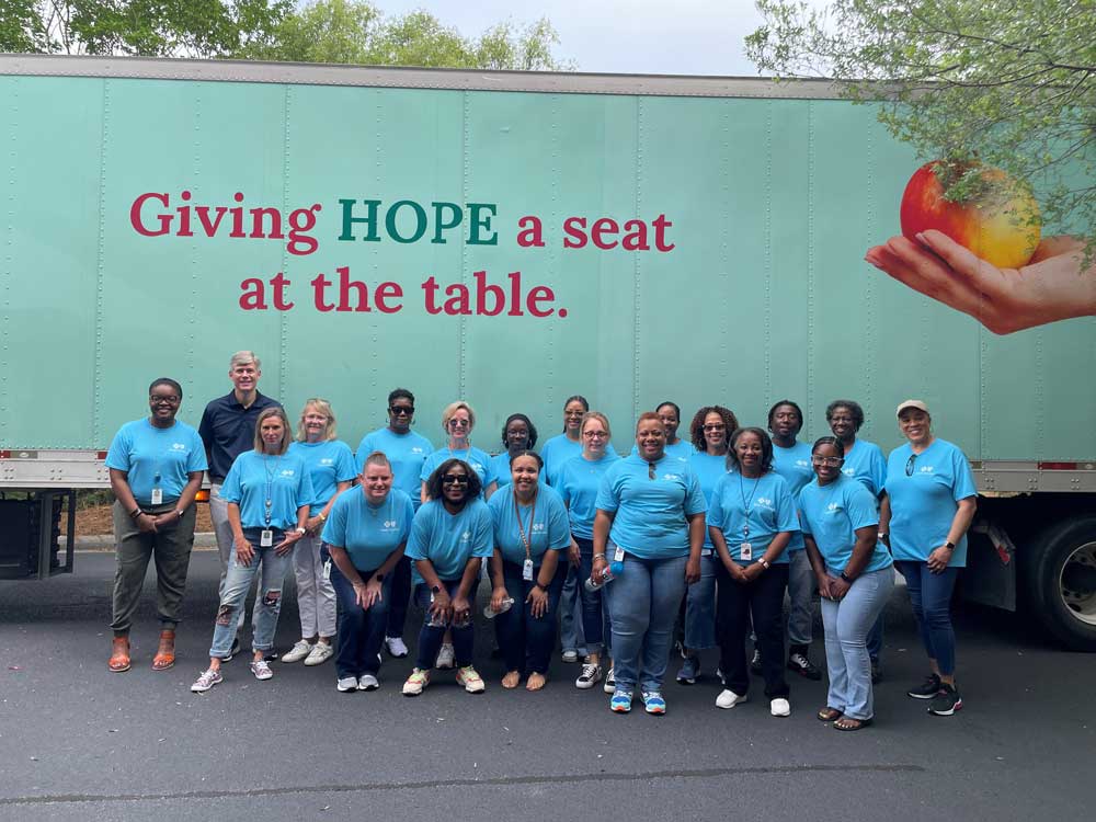 group of employees wearing blue cross in front of truck